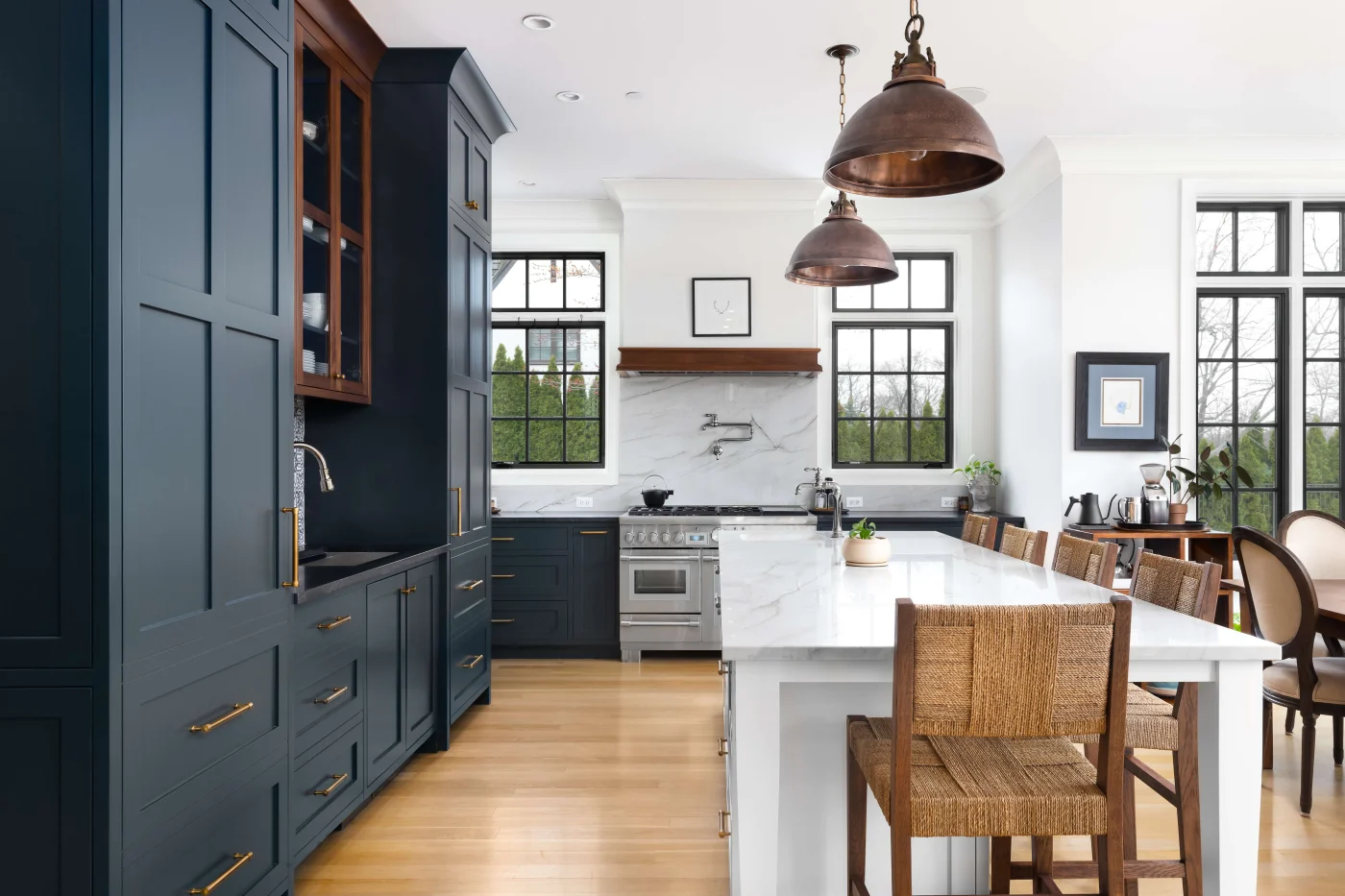 This stunningly updated kitchen combines deep blue custom cabinetry and a white marble waterfall island with warm wood accents, showcasing the high-end quality possible through thoughtful home improvements.